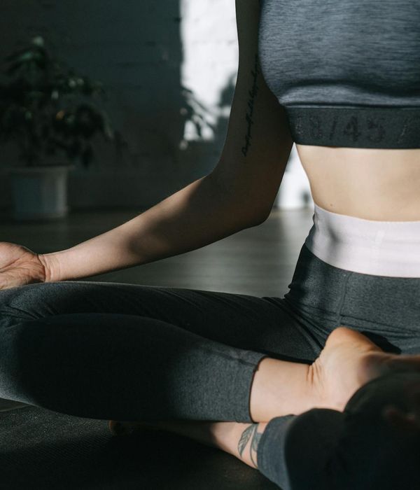 Woman in a peaceful yoga pose in a bright, minimalist room.